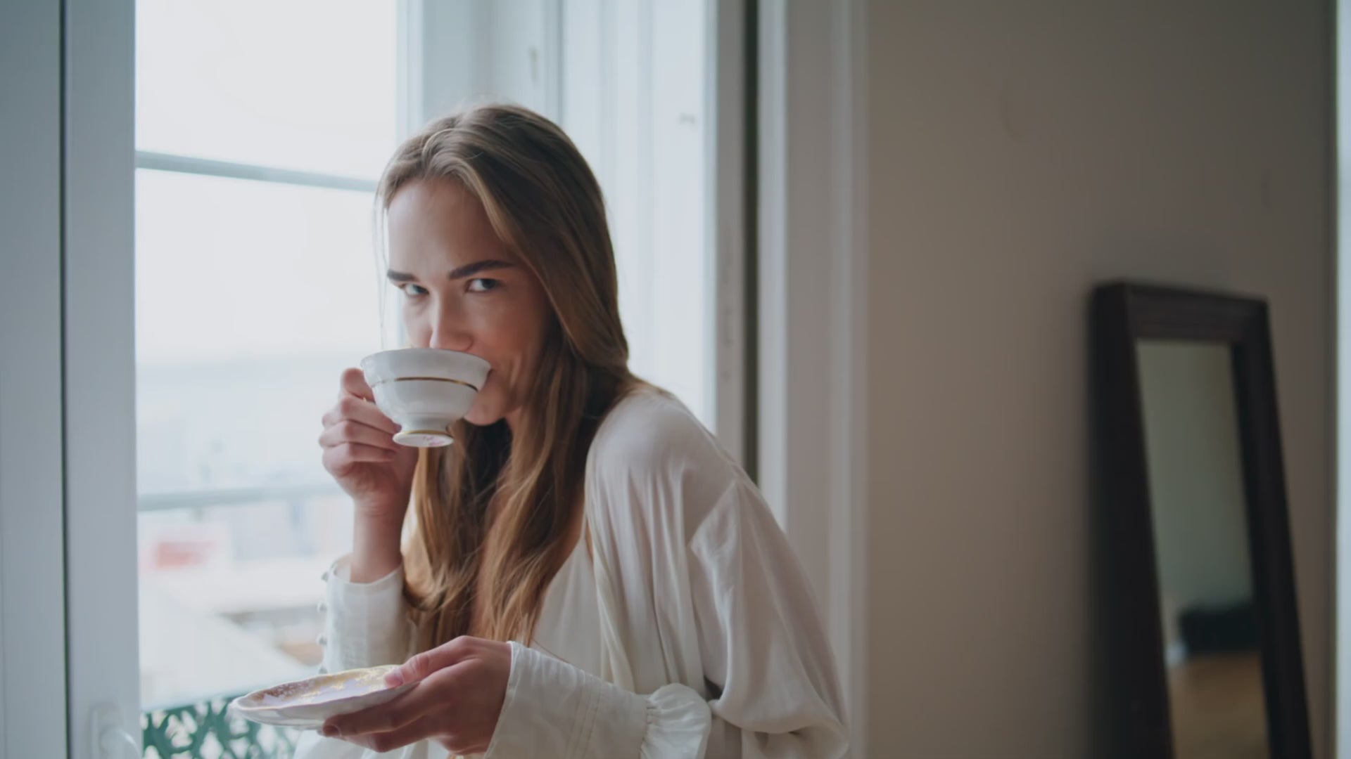 Load video: Woman enjoying a freshly brewed coffee at home by the window
